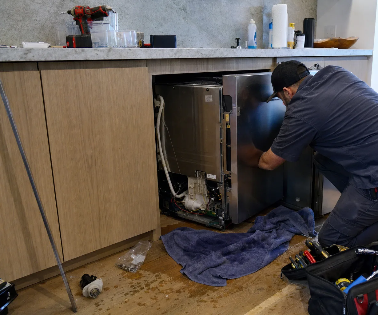 Technician servicing a built-in dishwasher up close